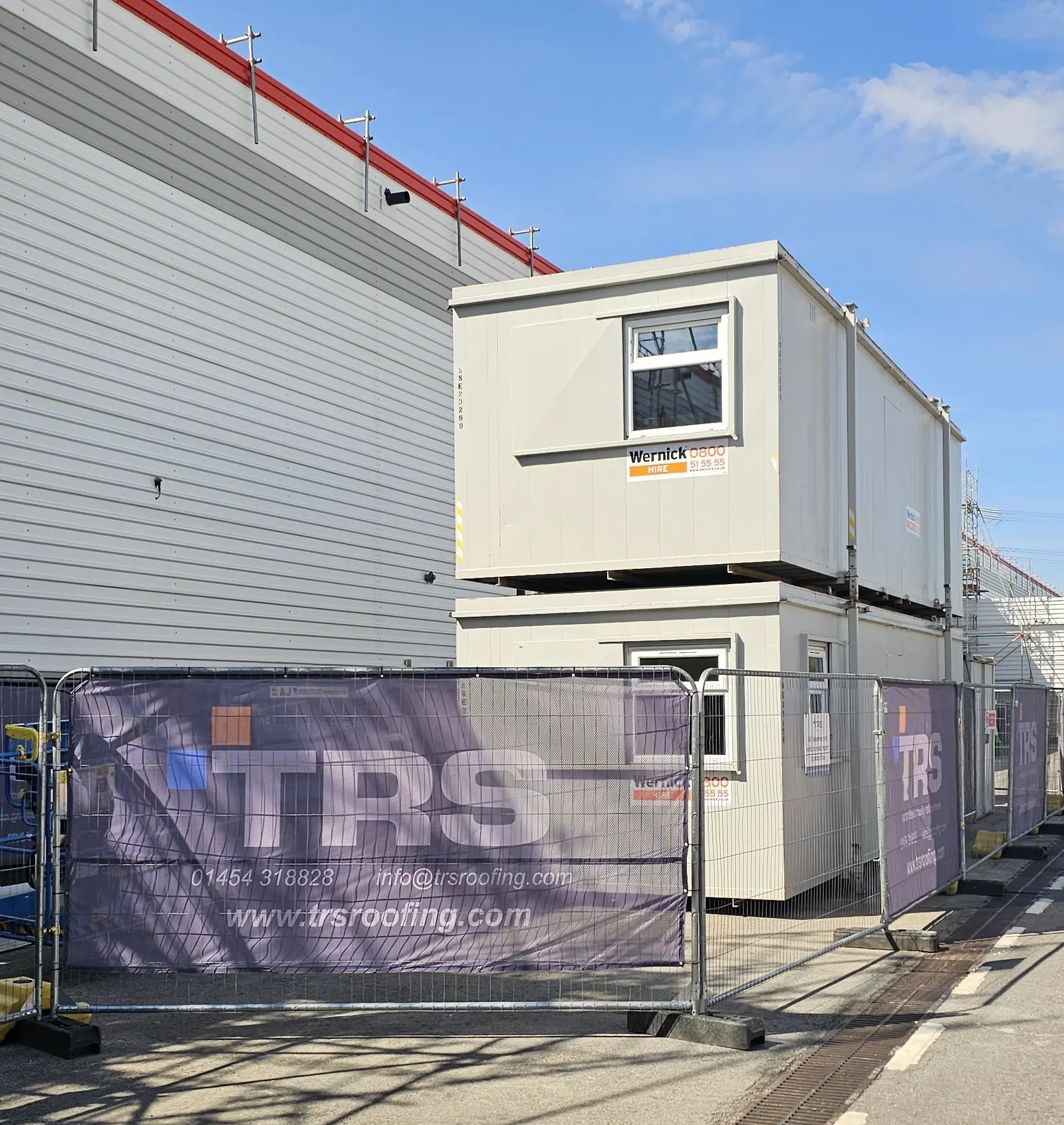 TRS site compound with branded fencing and welfare units on a live public-sector roof project
