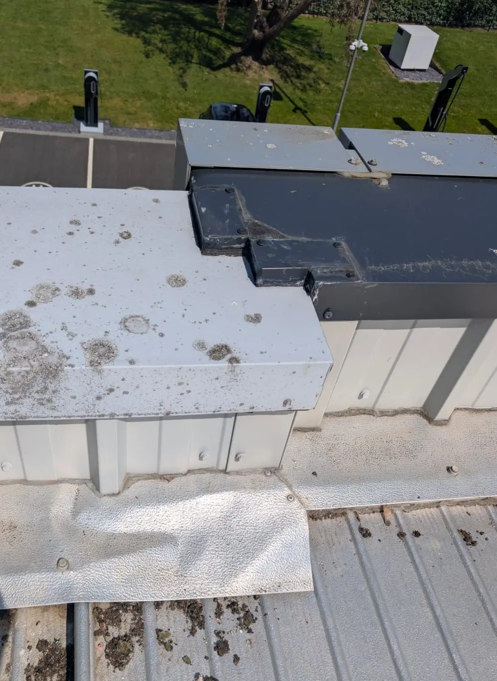 Failed metal roof cappings and edge details showing dirt, staining and weathering on a commercial roof