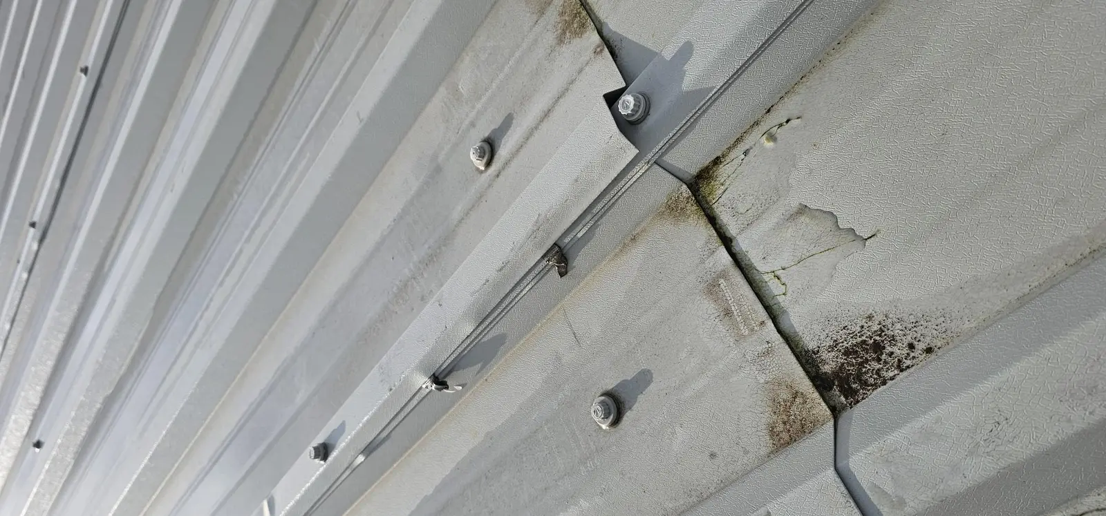 Close-up of metal roof sheeting showing poor detailing, gaps and dirt that can allow water tracking
