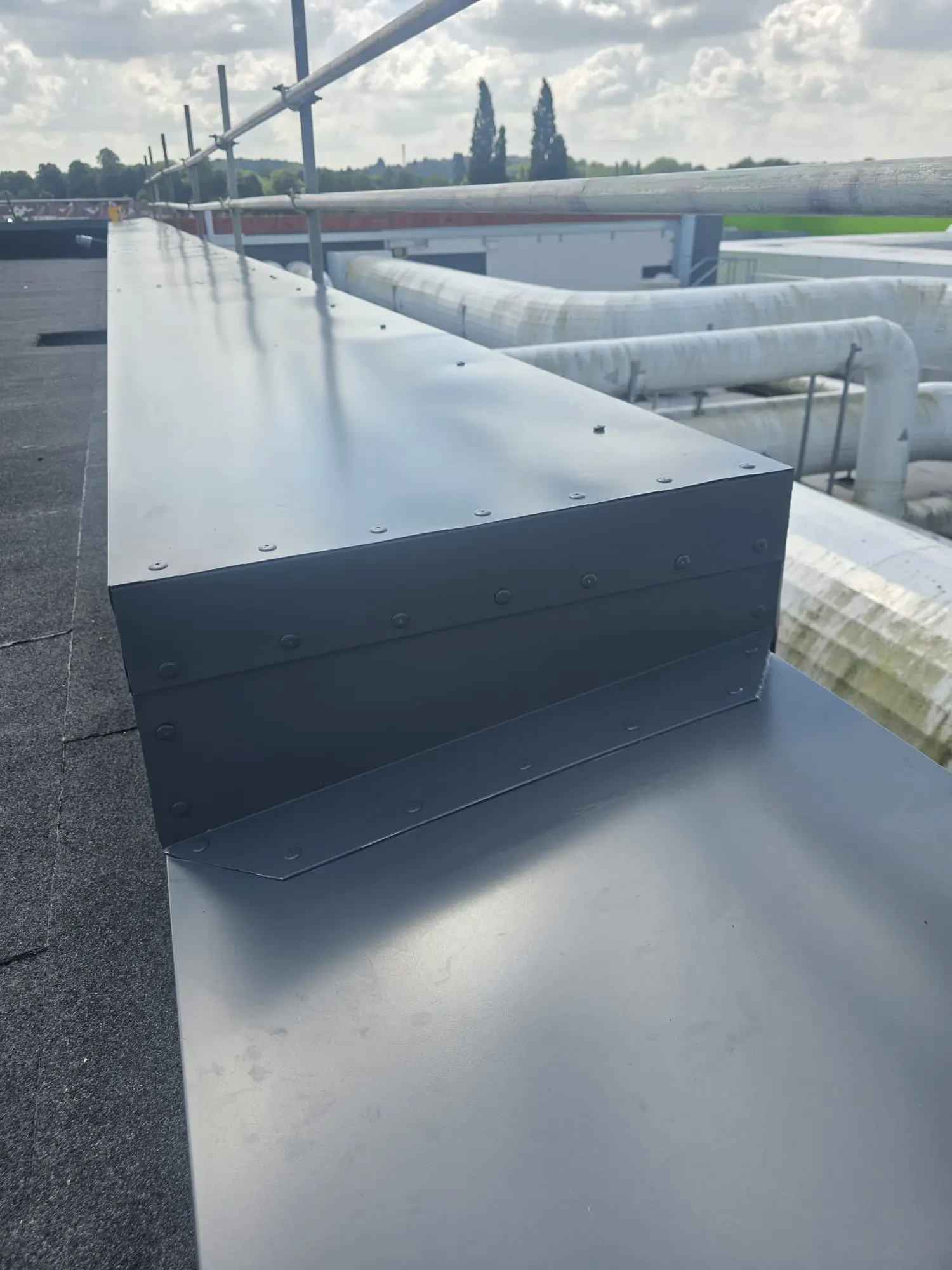 New dark grey metal parapet flashing installed on a commercial flat roof