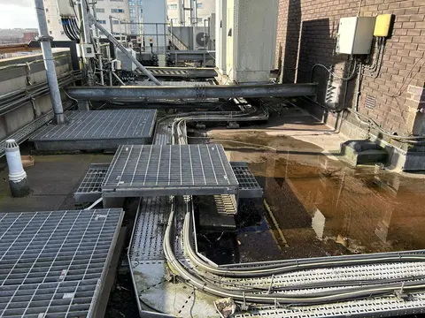 Hospital roof plant area with significant ponding water highlighting water-ingress and equipment risks