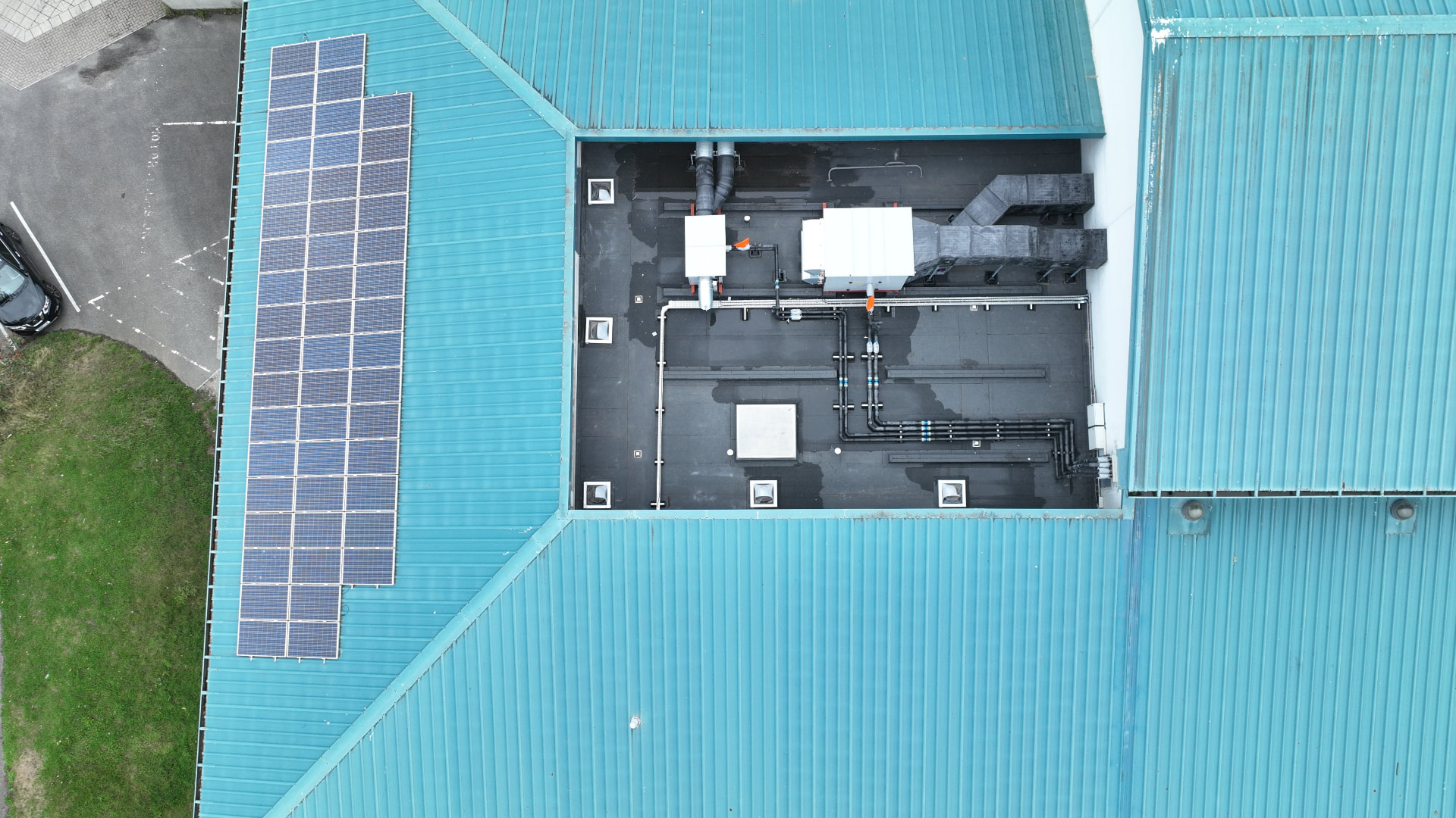 Central flat roof and surrounding blue pitched metal roofs at Pool Academy before works