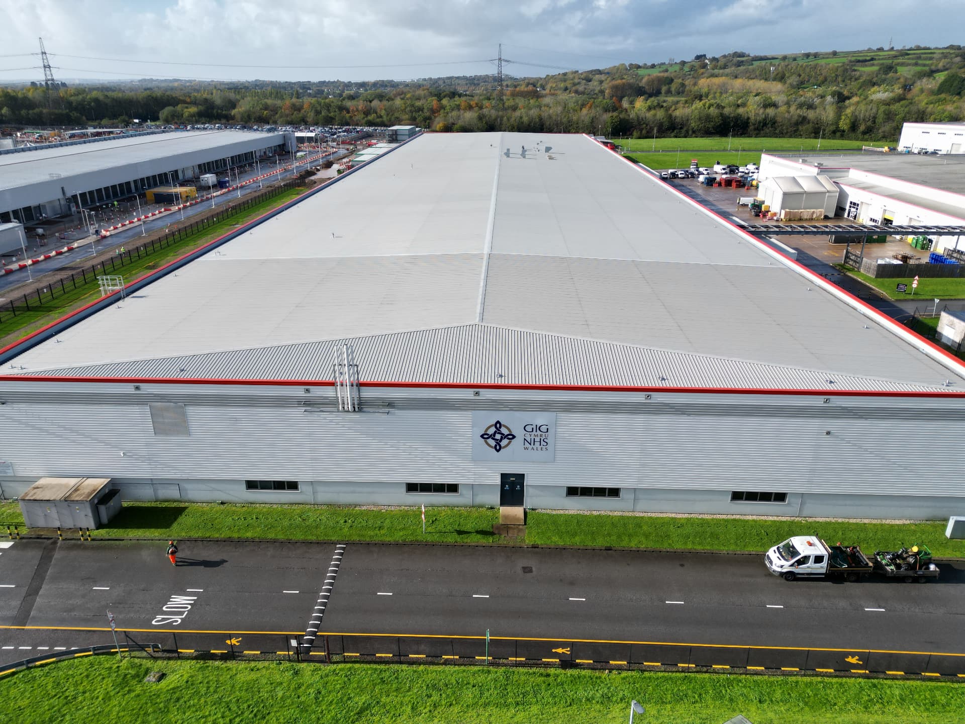 Aerial view of the completed metal roof and the NHS Wales branded facade at the logistics warehouse in Newport